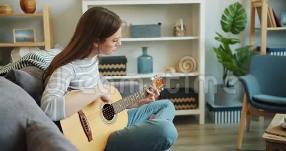 有魅力的女孩独自在公寓里弹吉他享受音乐视频的预览图