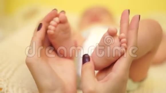 特写镜头妈妈轻轻地把婴儿的双脚握在手里视频的预览图