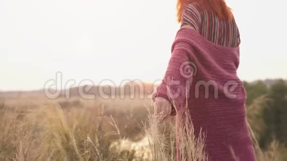 女人手触摸场日落时独自一人在收割场散步大自然中的孤独慢动作视频的预览图
