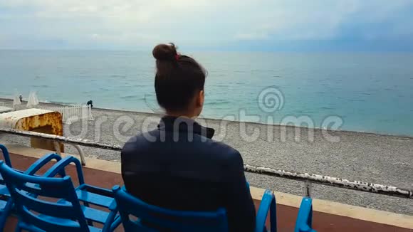 女人坐在空荡荡的海边沙滩上放松度假孤独悲伤视频的预览图