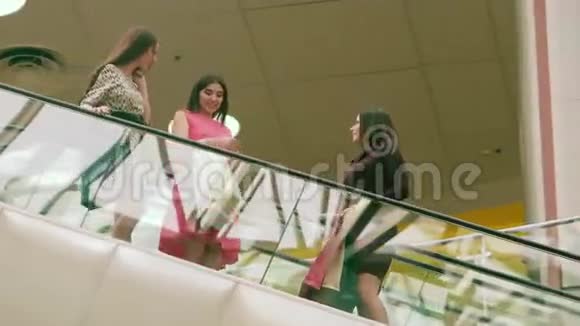 三个幸福的女人在楼下的自动扶梯上享受他们的购物日视频的预览图