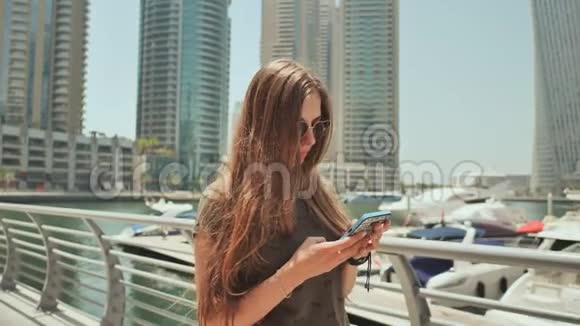一个长发女孩在迪拜码头的智能手机上拨了一条信息视频的预览图