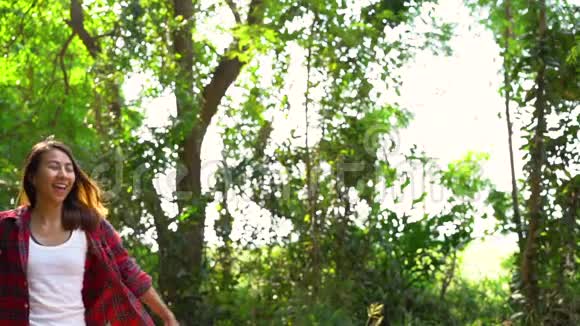 慢动作快乐的年轻亚洲女性旅行者与背包步行在森林视频的预览图