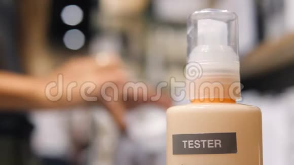 在购物中心的化妆品超市里年轻的混血女顾客在手皮上测试防晒霜4K视频的预览图