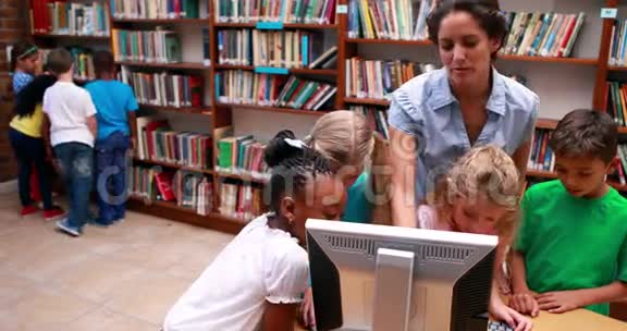 学生们和老师一起看图书馆里的电脑视频的预览图