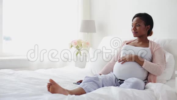 怀孕的非洲妇女在床上看电视视频的预览图