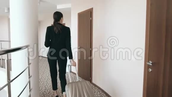 一位穿着裙子高跟鞋带着手提箱沿着酒店大堂散步的商务女性的后景肖像视频的预览图