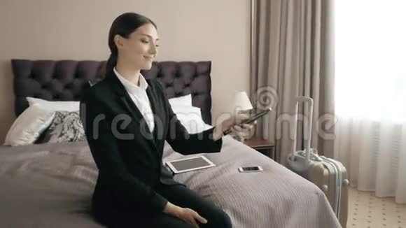 年轻商务女性在酒店房间放松看电视选择带有遥控器的香奈儿视频的预览图
