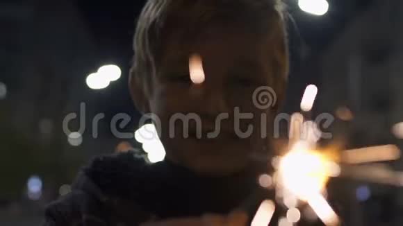 圣诞前夜快乐的男孩举着点燃的烟花与家人一起庆祝视频的预览图