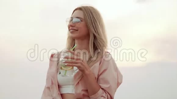 戴太阳镜的女孩喝夏季城市鸡尾酒微笑视频的预览图