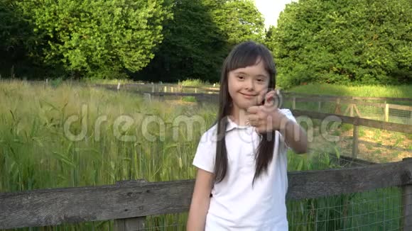 唐氏综合症女孩在公园里竖起大拇指微笑视频的预览图