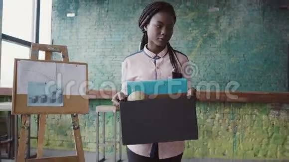 年轻的非洲妇女被解雇女性走过办公室带着私人物品的盒子视频的预览图