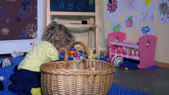 可爱的小女孩把所有的玩具都放进柳条篮子里孩子整理房间视频的预览图