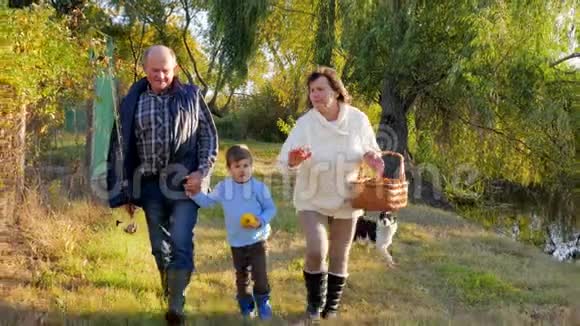 一家人散步快乐的祖父母带着孙子和狗周末到湖边钓鱼视频的预览图