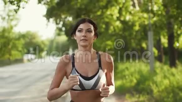 运动员的特写肖像那个女孩在日落时沿着马路跑在大自然中做运动的年轻女人慢慢慢慢视频的预览图