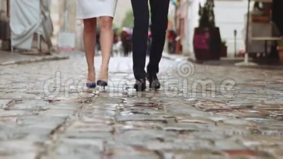 很少有一对年轻夫妇在伞下沿着老城的街道散步一起欢笑和快乐视频的预览图