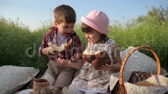 男孩用面包店的产品喂养女孩可爱的孩子分享面包野餐的产品孩子们玩得开心视频的预览图