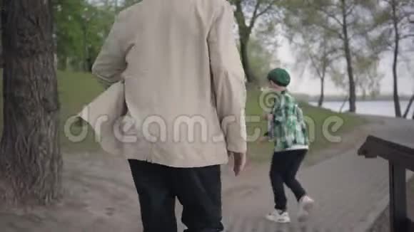 小男孩在公园里从爷爷身边跑开老人追着男孩但他累了停下来视频的预览图