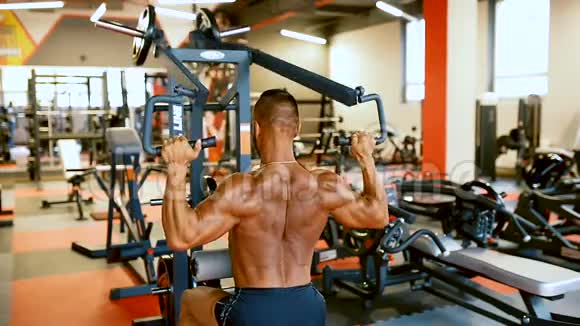 英俊的运动员正在健身房锻炼健美男子硬训练肌肉在训练机器视频的预览图
