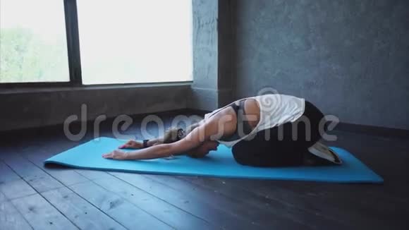 在健身俱乐部做瑜伽垫伸展腿筋的年轻女子视频的预览图