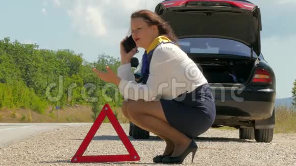 女人紧张地在一辆破车旁边打电话视频的预览图