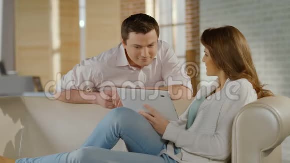 快乐的年轻夫妇在平板电脑上看家庭照片回忆视频的预览图