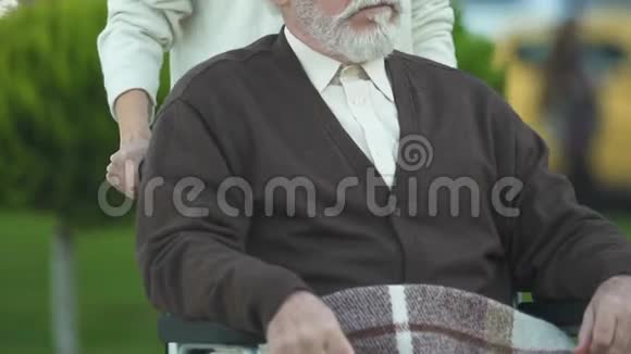 女性推着轮椅的老人护理特写中的关怀和同情视频的预览图