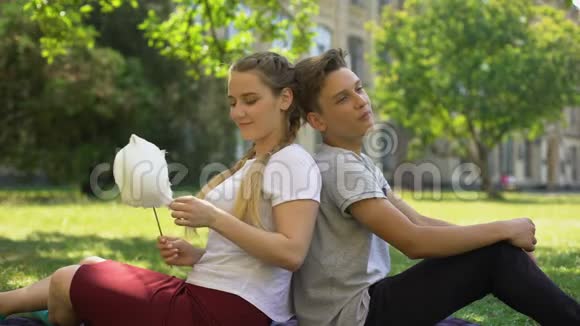 有趣的青少年背靠背坐在一起一边吃棉花糖一边胡闹视频的预览图