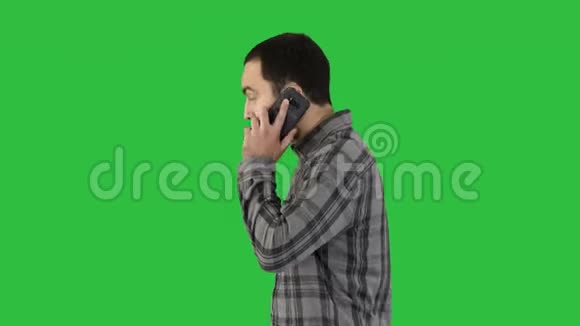 帅气的年轻人留着胡子在绿色屏幕上用手机边走边聊色度键视频的预览图
