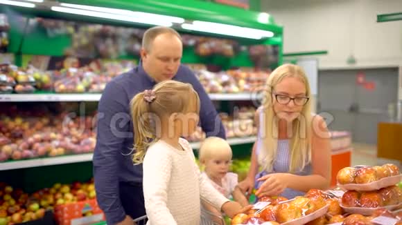 快乐的一家人在购物一家四口路过的水果店家庭在超市购物视频的预览图
