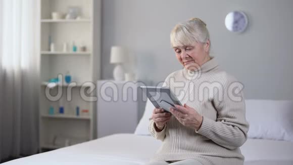 悲伤的老妇人看着丈夫的照片坐在客厅的床上视频的预览图