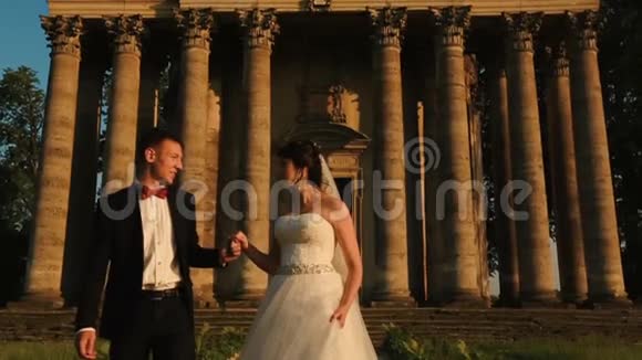 在巴洛克式建筑的背景下温柔地亲吻了一对迷人的新婚夫妇视频的预览图
