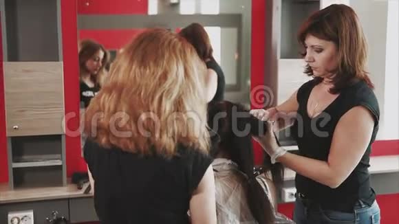 理发师为美容院的一位年轻顾客准备染发视频的预览图