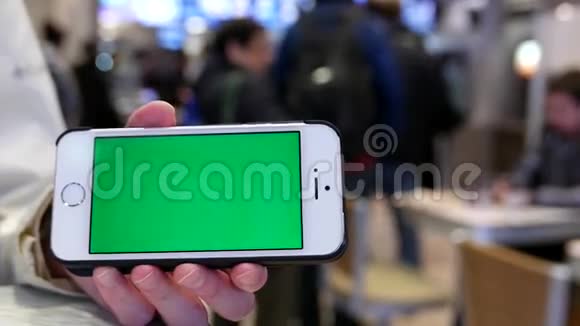 女人手里拿着绿色屏幕的iphone模糊的人点菜视频的预览图