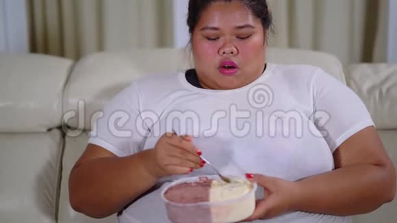 超重的女人在沙发上享受冰淇淋视频的预览图