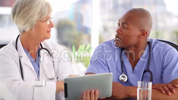 成熟的医生在触摸屏前和护士交谈视频的预览图