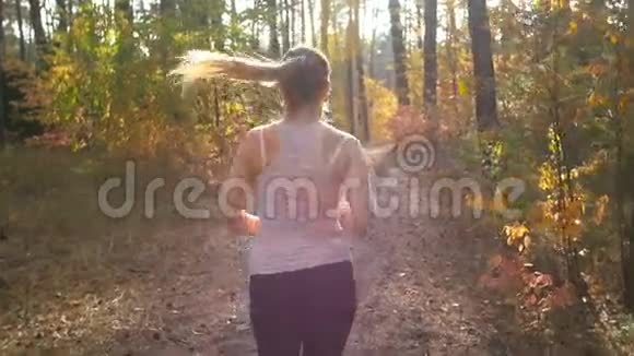 后景慢镜头带马尾辫的年轻女子在森林里奔跑视频的预览图