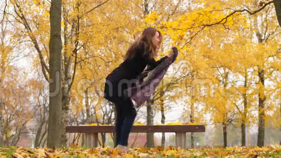 快乐的女人在秋天公园疯狂跳舞鲜艳的枫树视频的预览图
