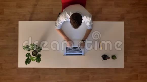从上到下拍摄时间间隔男性在木制办公室使用笔记本电脑坐在办公桌前一天开始和结束视频的预览图