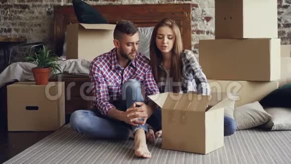 幸福的一对夫妇在搬迁后打开盒子一起看照片谈笑风生视频的预览图