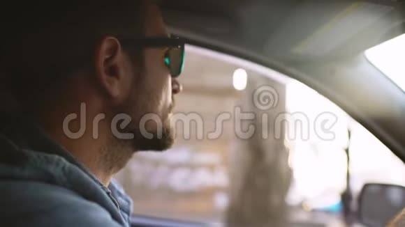 戴着镜子墨镜带着胡须的英俊男子驾驶着太阳照的汽车视频的预览图