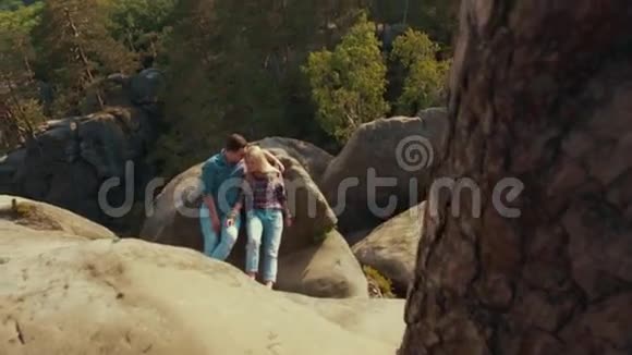 好看的年轻人穿着休闲装可爱的年轻情人躺在森林环绕的山石上视频的预览图