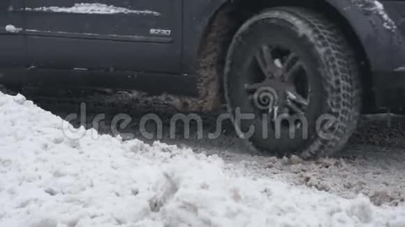 在下雪的白天带冬天轮胎的越野车在雪道上行驶慢动作的车轮特写恶劣天气视频的预览图