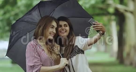 自拍时间为两位女士在下雨天用手机拍照伞下4k视频的预览图
