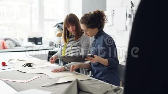 有吸引力的服装设计师企业家们正在用粉笔勾勒出剪裁用平板电脑和谈话忙碌的一天视频的预览图