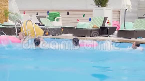 参加夏季派对的朋友们在蓝色的水中玩得很开心把水溅到游泳池里视频的预览图
