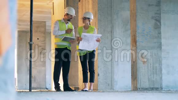 女性和男性建筑师工程师正在一个建筑工地上交谈视频的预览图