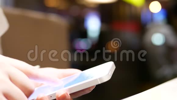 女人用她的手机在美丽模糊的灯光背景下视频的预览图