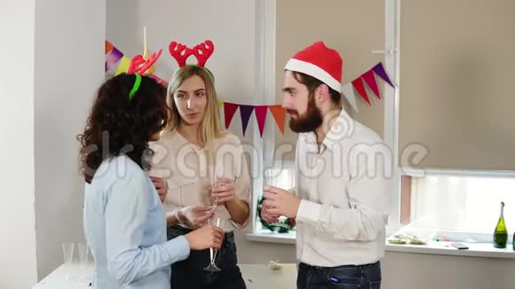 年轻的上班族在圣诞派对期间一边在办公室里说话一边拿着酒杯一边喝着起泡葡萄酒视频的预览图