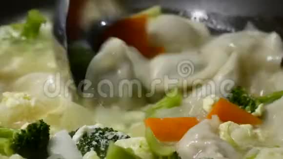 靠近一个女人在煎锅里煮蔬菜和饺子汤视频的预览图